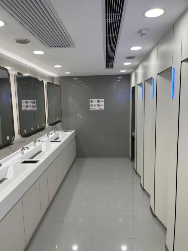 White HPL toilet cubicle for commercial spaces with LED lighting in a modern, high-traffic restroom setting.